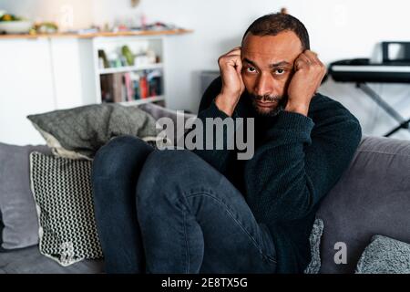 Depresso uomo di 40 anni seduto sul divano a. casa Foto Stock