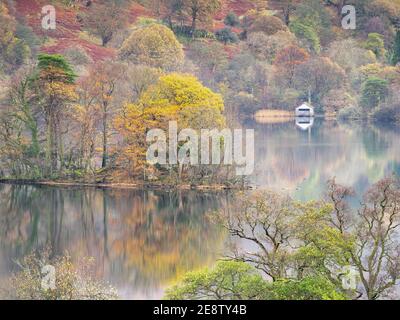 Il colore autunnale si riflette in Rydal Water in una tranquilla mattinata di novembre, con l'iconica boathouse visibile sulla riva opposta. Foto Stock