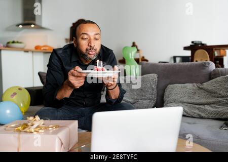 Bell'uomo di 40 anni che soffia candele nel suo compleanno torta Foto Stock