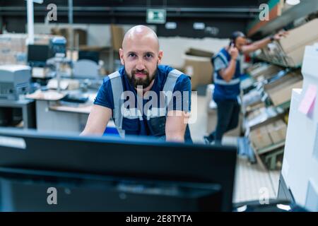 commissionatore di 30 anni che lavora su un computer a. il magazzino Foto Stock