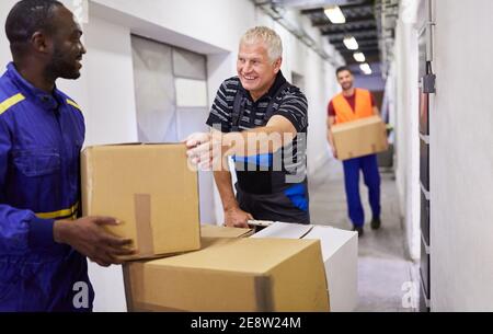 Gruppo multiculturale di lavoratori presso il reparto merci in arrivo trasporti pacchetti su carrelli a spinta Foto Stock