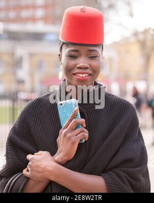 Giovane donna nera amante della moda con cappello alla moda in outfit elegante fuori dal London Fashion Weekend, Chelsea, Londra, Regno Unito Foto Stock