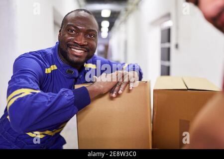 Operaio africano come un mini jobber o lavoratore temporaneo con pacchi presso un'azienda di spedizioni Foto Stock