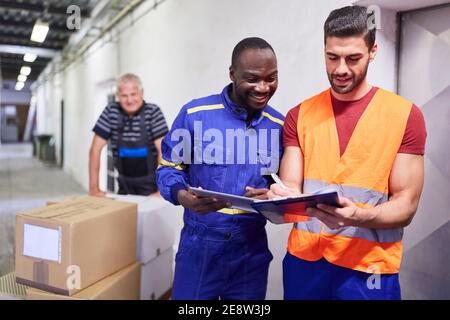 L'addetto del magazzino in entrata controlla la consegna dei pacchetti con la lista di controllo sulla clipboard Foto Stock