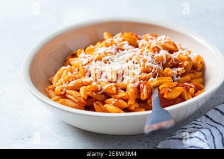 Gnocchetti sardi in salsa di pomodoro con formaggio, fondo grigio. Concetto di cucina italiana Foto Stock