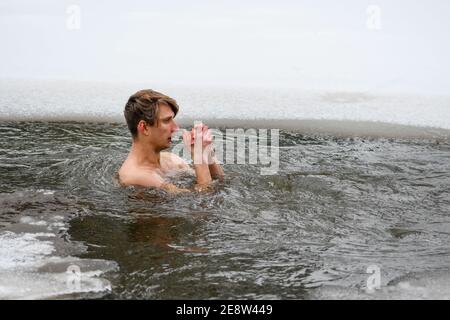 Ragazzo o uomo che bagna e nuota nelle acque fredde di un lago o di un fiume, la terapia fredda, il nuoto del ghiaccio Foto Stock