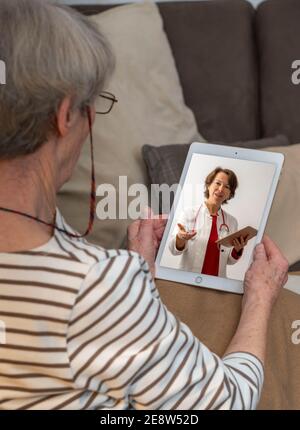 Immagine simbolica di telemedicina, paziente anziano parla con un medico in una videoconferenza, da casa, Foto Stock