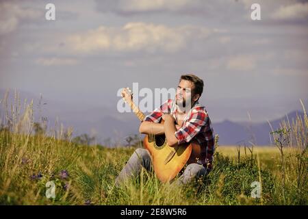 Uniti alla natura. Musicista alla ricerca di ispirazione. Vagabondo sognante. Umore tranquillo. Ragazzo con chitarra contempla la natura. Concetto di Wanderlust. Natura ispiratrice. Vacanze estive. In cerca di musa. Foto Stock