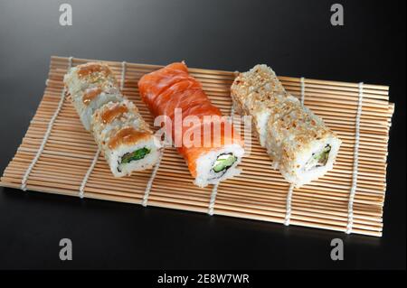 3 pezzi di sushi rotola su tappeto di bambù Foto Stock