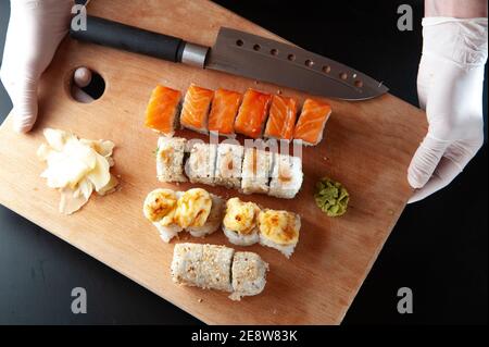 Lo chef tiene un set di sushi con zenzero e wasabi su una tavola di legno. Foto Stock