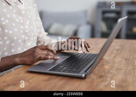 Primo piano di una donna afroamericana irriconoscibile che usa un computer portatile alla scrivania mentre lavora da casa in appartamento, copia spazio Foto Stock
