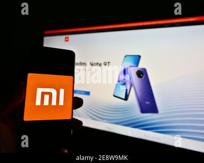 Persona che detiene smartphone con il logo aziendale della società cinese di elettronica Xiaomi Corporation in esposizione. Mettere a fuoco lo schermo del telefono cellulare. Foto Stock