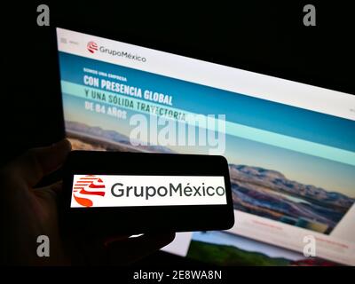 Persona che detiene il telefono cellulare con il logo della società messicana mineraria e di trasporto Grupo México sullo schermo di fronte al sito web. Mettere a fuoco il display del telefono. Foto Stock