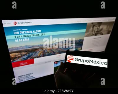 Persona che tiene il telefono con il logo della società messicana mineraria e di trasporto Grupo México sullo schermo di fronte al sito web. Focus sul monitor del telefono cellulare. Foto Stock