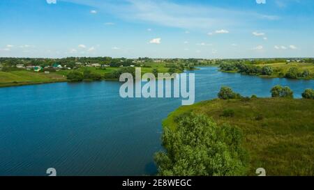 Vista panoramica aerea del fiume e dei campi verdi nella campagna russa. Paesaggio naturale della curva del fiume e lussureggianti alberi verdi. Foto Stock