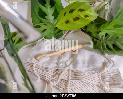 Essenziale per il bagno senza plastica. Spazzolino da denti di bambù e linguette dentali accanto a un lavabo. Uno stile di vita ecocompatibile e una cura personale sostenibile si scambiano. Foto Stock
