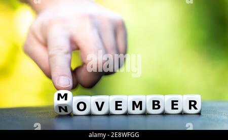 La mano trasforma i dadi e cambia la parola novembre in Movember. Movember è un evento annuale per sensibilizzare gli uomini sui problemi di salute. Foto Stock