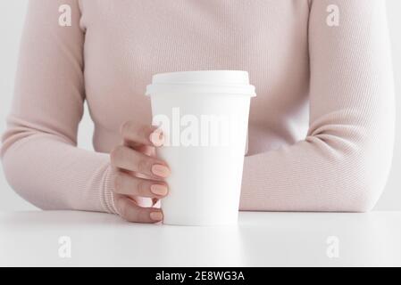 Donna che tiene il mockup bianco della tazza di carta del caffè. Foto Stock