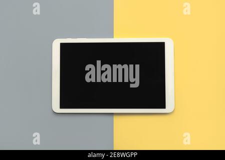 Tablet digitale bianco con schermo nero su giallo e grigio sfondo Foto Stock