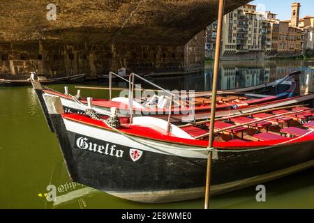 due piccole barche colorate, di nome guelfo e ghibellino, appartenenti ai renaioli di firenze parcheggiati sotto il ponte vecchio Foto Stock