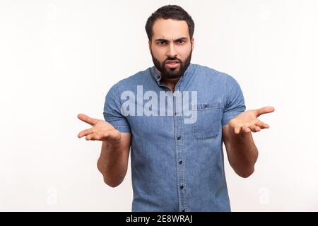 Infastidito uomo stressato con la barba che chiede che cosa volete e che sparge le mani, seriamente guardando la macchina fotografica, la disputa della famiglia, l'incomprensione. Stu. Interno Foto Stock