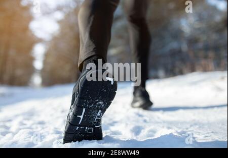 Attività invernali all'aperto. Atleta maschile in scarpe sportive jogging al parco durante la giornata invernale innevata, vista closeup. Spazio di copia Foto Stock