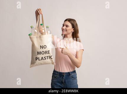 Niente più plastica. Donna millenaria che punta alla borsa Eco con bottiglie vuote Foto Stock