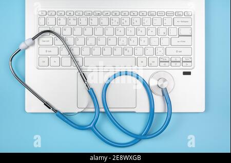 Online medico consulenza tecnologia in laptop. Notebook, notebook con stetoscopio su sfondo blu. Hardware sano. Concetto di telemedicina. Inizio pagina Foto Stock