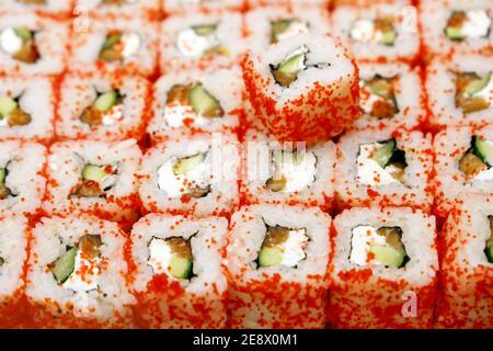Involtini di sushi con anguilla, cetriolo e formaggio cremoso, cosparsi di roe di pesce volante Foto Stock