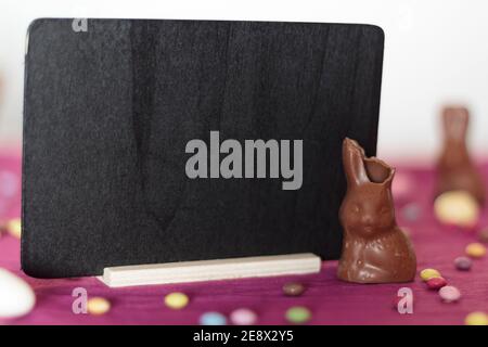 Il coniglietto al cioccolato manca un morso e una lavagna con spazio per la copia Foto Stock