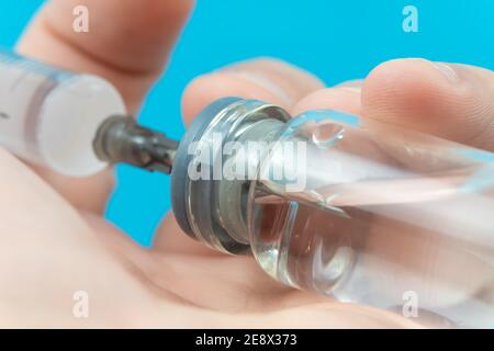 La mano dell'uomo compone la medicina usando una siringa con un ago da un flacone medico, macrofotografia. Concetto di medicina, vaccinazione Foto Stock