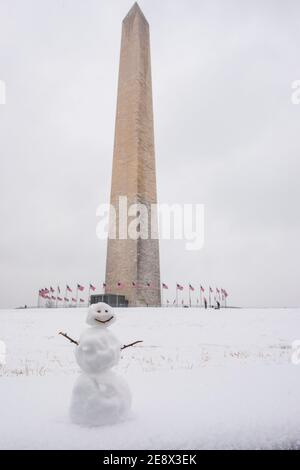 Un simpatico pupazzo di neve sorride ai visitatori di fronte al Washington Monument durante una giornata invernale innevata a Washington, D.C. Foto Stock