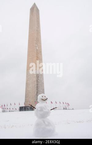 Un simpatico pupazzo di neve sorride ai visitatori di fronte al Washington Monument durante una giornata invernale innevata a Washington, D.C. Foto Stock