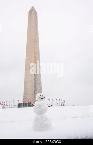 Un simpatico pupazzo di neve sorride ai visitatori di fronte al Washington Monument durante una giornata invernale innevata a Washington, D.C. Foto Stock