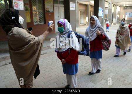 I funzionari della scuola controllano la temperatura corporea degli studenti e sanitizzando le mani prima di entrare a scuola come misura preventiva contro la diffusione del coronavirus (COVID-19), a Peshawar lunedì 01 febbraio 2021. Le scuole primarie e medie e le università in tutto il Pakistan hanno riaperto oggi (lunedì) dopo un intervallo di quasi tre mesi mentre il paese continua a combattere la seconda ondata della pandemia del coronavirus. Foto Stock