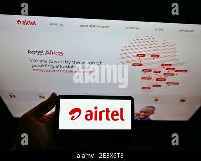 Persona in possesso di smartphone con il logo del provider di telecomunicazioni Airtel Africa plc in esposizione davanti al sito Web. Mettere a fuoco lo schermo del telefono cellulare. Foto Stock