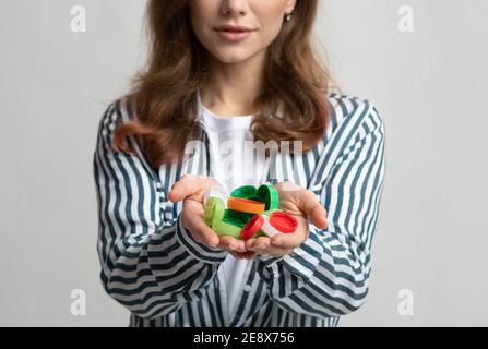 Unriconoscable Lady che tiene i coperchi colorati di plastica tazze bottiglia in mani Foto Stock