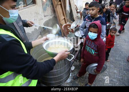 Gaza, Palestina. 01 Feb 2021. Il cuoco volontario palestinese distribuisce cibo preparato con ingredienti ottenuti da donatori, per aiutare le famiglie bisognose in un quartiere povero della città di Gaza, il 1 febbraio 2021. (Foto di Mahmoud Khattab/INA Photo Agency/Sipa USA) Credit: Sipa USA/Alamy Live News Foto Stock