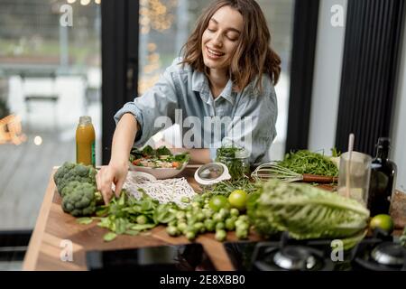Donna che cucina sana insalata verde in cucina Foto Stock