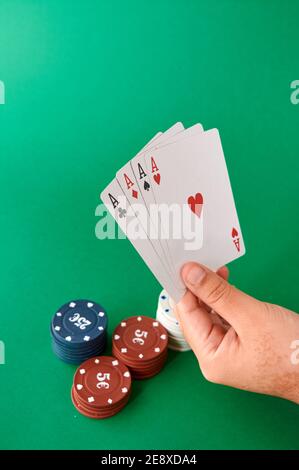 Pila di chip e mano con quattro assi, stoffa di Poker, un mazzo di carte, mano di poker e chip. Sfondo. Foto Stock