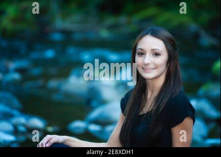 Una giovane donna si pone lungo le rive di un piccolo fiume. Foto Stock