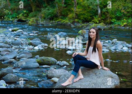 Teenager posa su una roccia lungo il fiume Salmon nel Mt. Hood National Forest Foto Stock