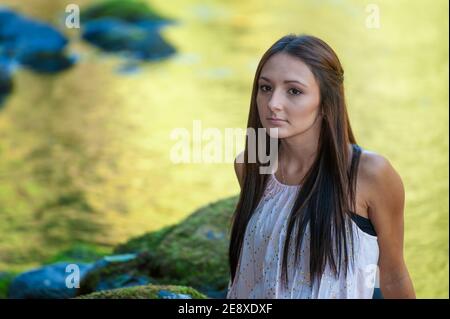 Una giovane donna si pone lungo le rive di un piccolo fiume. Foto Stock
