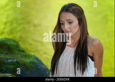 Una giovane donna si pone lungo le rive di un piccolo fiume. Foto Stock