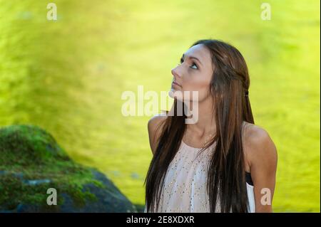 Una giovane donna si pone lungo le rive di un piccolo fiume. Foto Stock