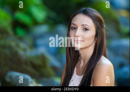 Una giovane donna si pone lungo le rive di un piccolo fiume. Foto Stock