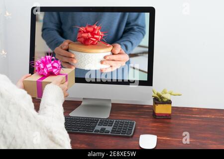 Foto dello schermo del computer che consegna un regalo a una persona al lavoro. Scambio virtuale di regali. Foto Stock