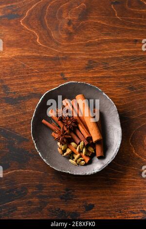 Bastoncini di cannella naturali assortiti, grani di cardamomo, stelle di anice che cuocono ingredienti su uno sfondo marrone rustico. Spezie naturali. Foto Stock