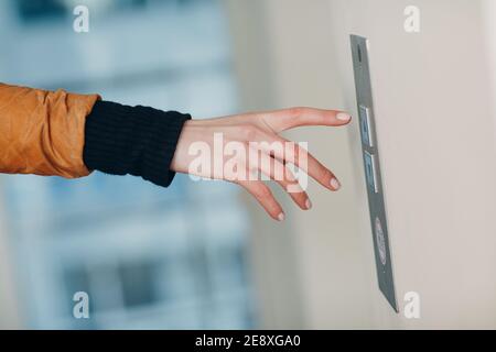 Primo piano dell'indice premendo il pulsante elevatore durante il coronavirus pandemic covid-19 Foto Stock