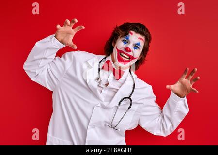 felice attore medico mime in un cappotto bianco e cravatta rossa di prua utilizzando stetoscopio, concetto sanitario Foto Stock